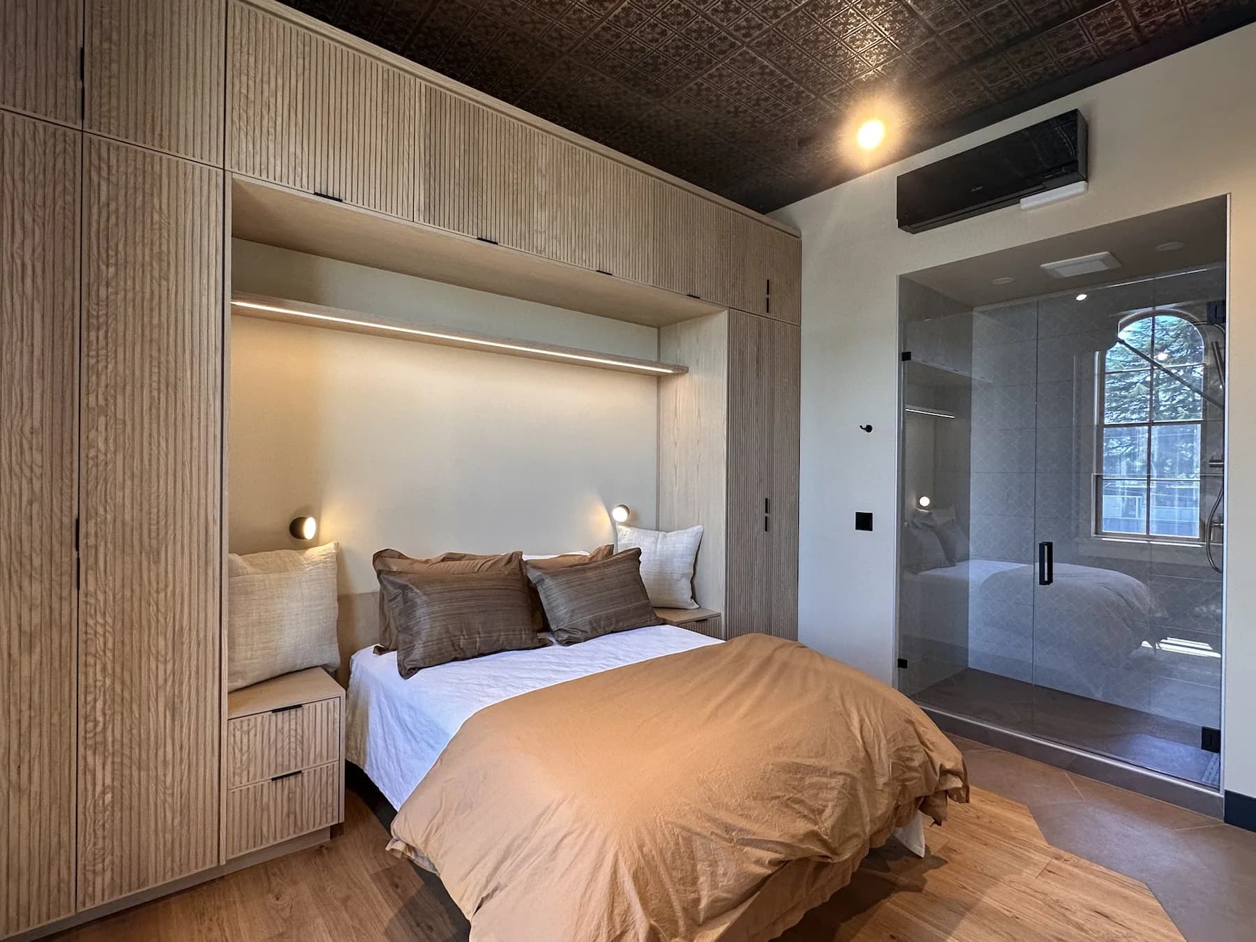 Bedroom suite with custom wood built-ins and glass shower